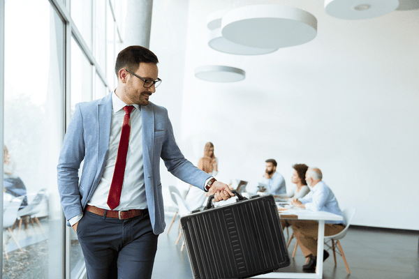 Guy holding black briefcase made out of metal walking away from work
