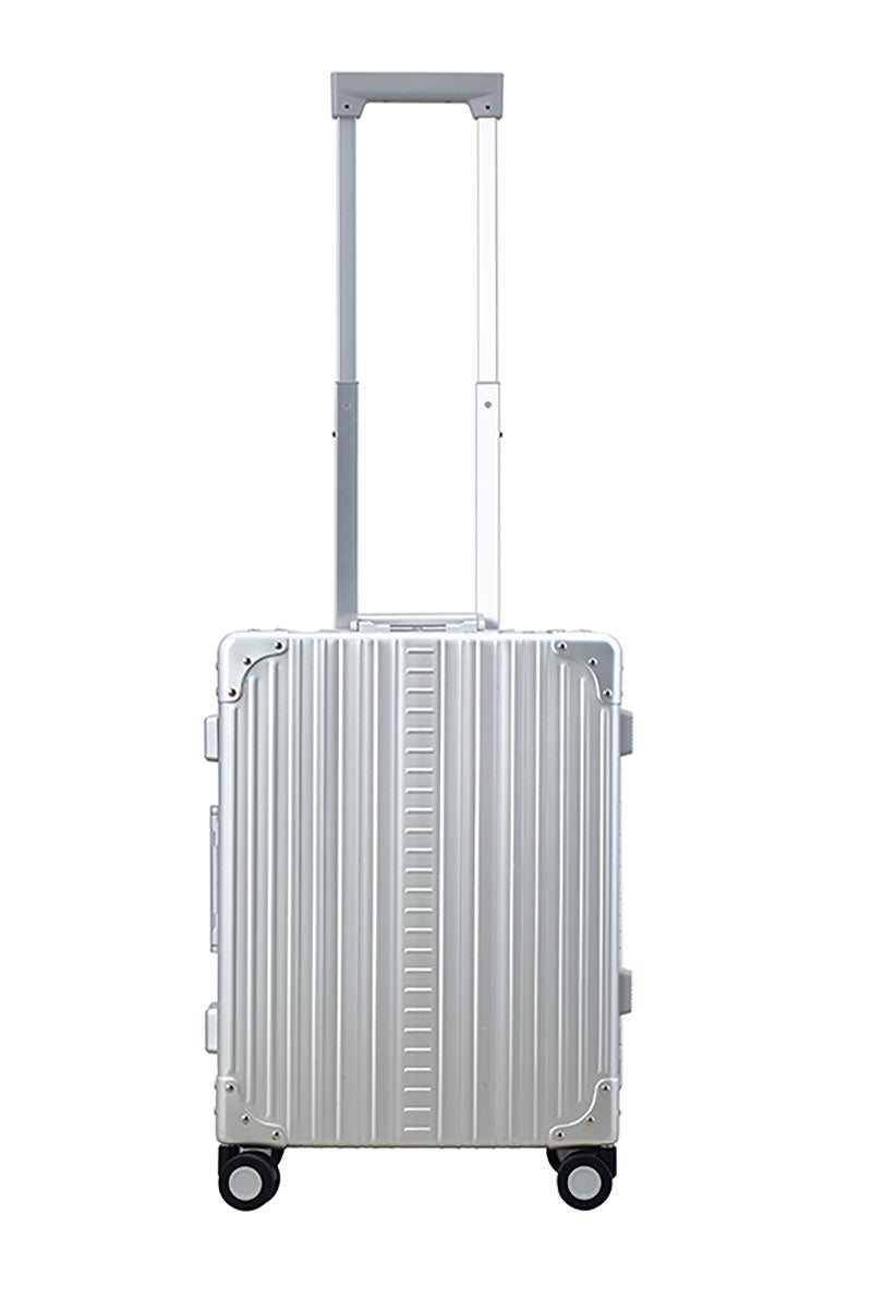 Platinum Silver Aleon aluminum luggage angled side profile showcasing full case design|The ALEON 21" Carry-On rests beside a plush airport lounge chair, its refined metallic finish complementing the sophisticated travel setting. Designed for durability and elegance, it exudes premium craftsmanship and functionality.|An open platinum ALEON 21" Carry-On reveals a neatly arranged interior with compre