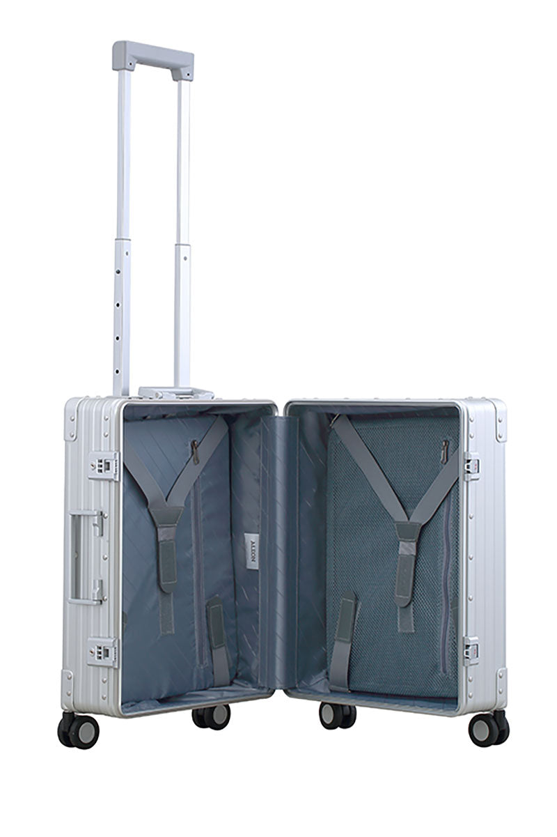 Platinum Silver Aleon aluminum luggage angled side profile showcasing full case design|The ALEON 21" Carry-On rests beside a plush airport lounge chair, its refined metallic finish complementing the sophisticated travel setting. Designed for durability and elegance, it exudes premium craftsmanship and functionality.|An open platinum ALEON 21" Carry-On reveals a neatly arranged interior with compre