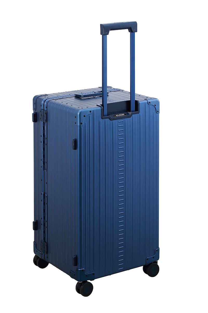 Sharpie Blue 30-inch Aluminum Trunk – International Checked Spinner Case|A close-up of the sapphire suitcase’s high-density double quad wheels, designed for smooth 360-degree rotation. The aluminum side handle is visible, offering an alternative carrying option for convenience.|The blue suitcase is fully opened, revealing a spacious interior with a fitted packing cube and a compression panel desig