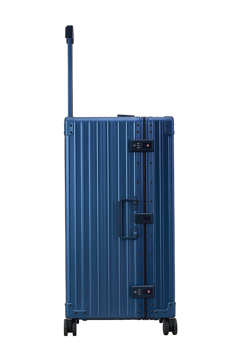 Sharpie Blue 30-inch Aluminum Trunk – International Checked Spinner Case|A close-up of the sapphire suitcase’s high-density double quad wheels, designed for smooth 360-degree rotation. The aluminum side handle is visible, offering an alternative carrying option for convenience.|The blue suitcase is fully opened, revealing a spacious interior with a fitted packing cube and a compression panel desig