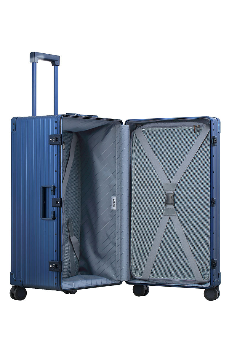 Sharpie Blue 30-inch Aluminum Trunk – International Checked Spinner Case|A close-up of the sapphire suitcase’s high-density double quad wheels, designed for smooth 360-degree rotation. The aluminum side handle is visible, offering an alternative carrying option for convenience.|The blue suitcase is fully opened, revealing a spacious interior with a fitted packing cube and a compression panel desig
