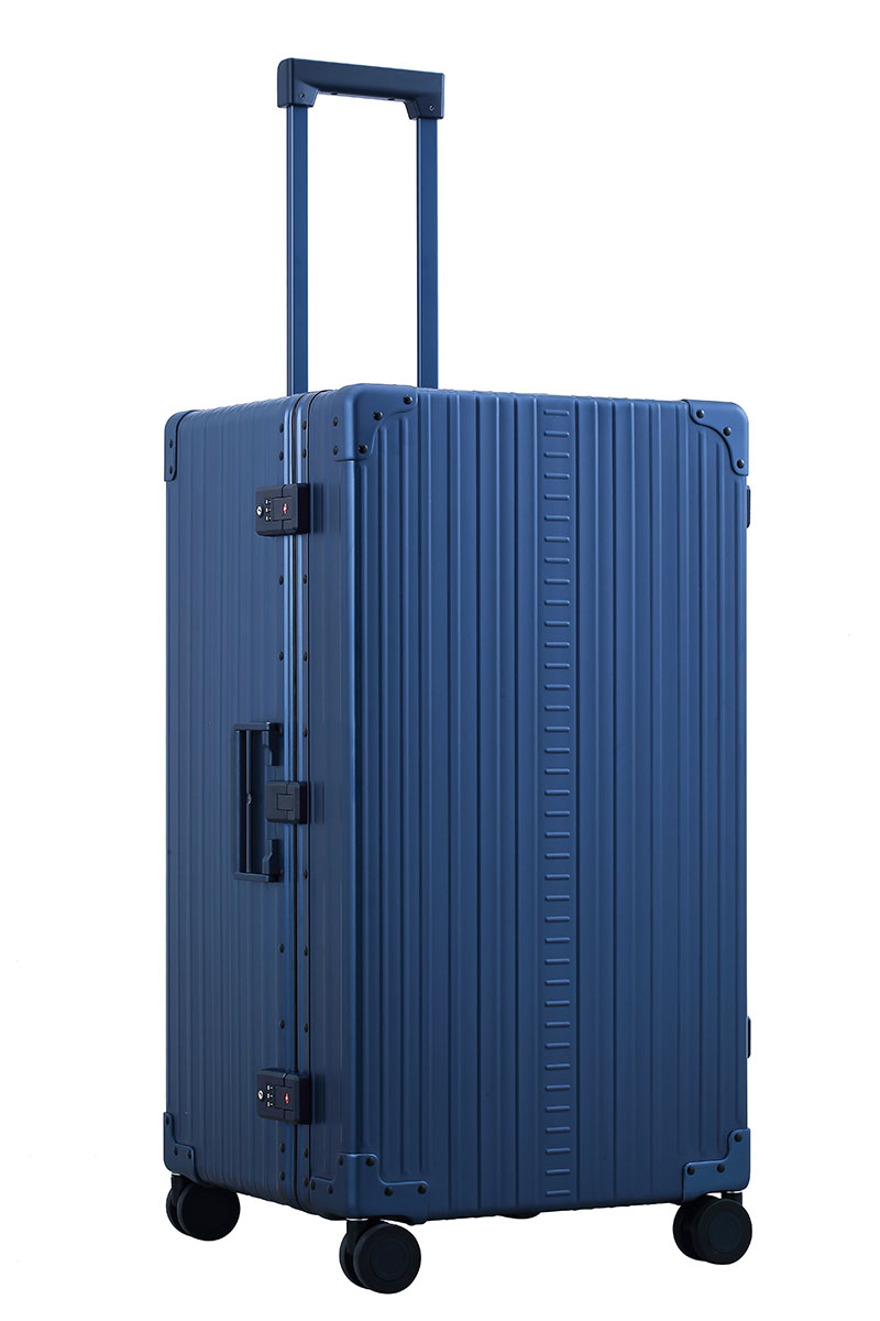 Sharpie Blue 30-inch Aluminum Trunk – International Checked Spinner Case|A close-up of the sapphire suitcase’s high-density double quad wheels, designed for smooth 360-degree rotation. The aluminum side handle is visible, offering an alternative carrying option for convenience.|The blue suitcase is fully opened, revealing a spacious interior with a fitted packing cube and a compression panel desig