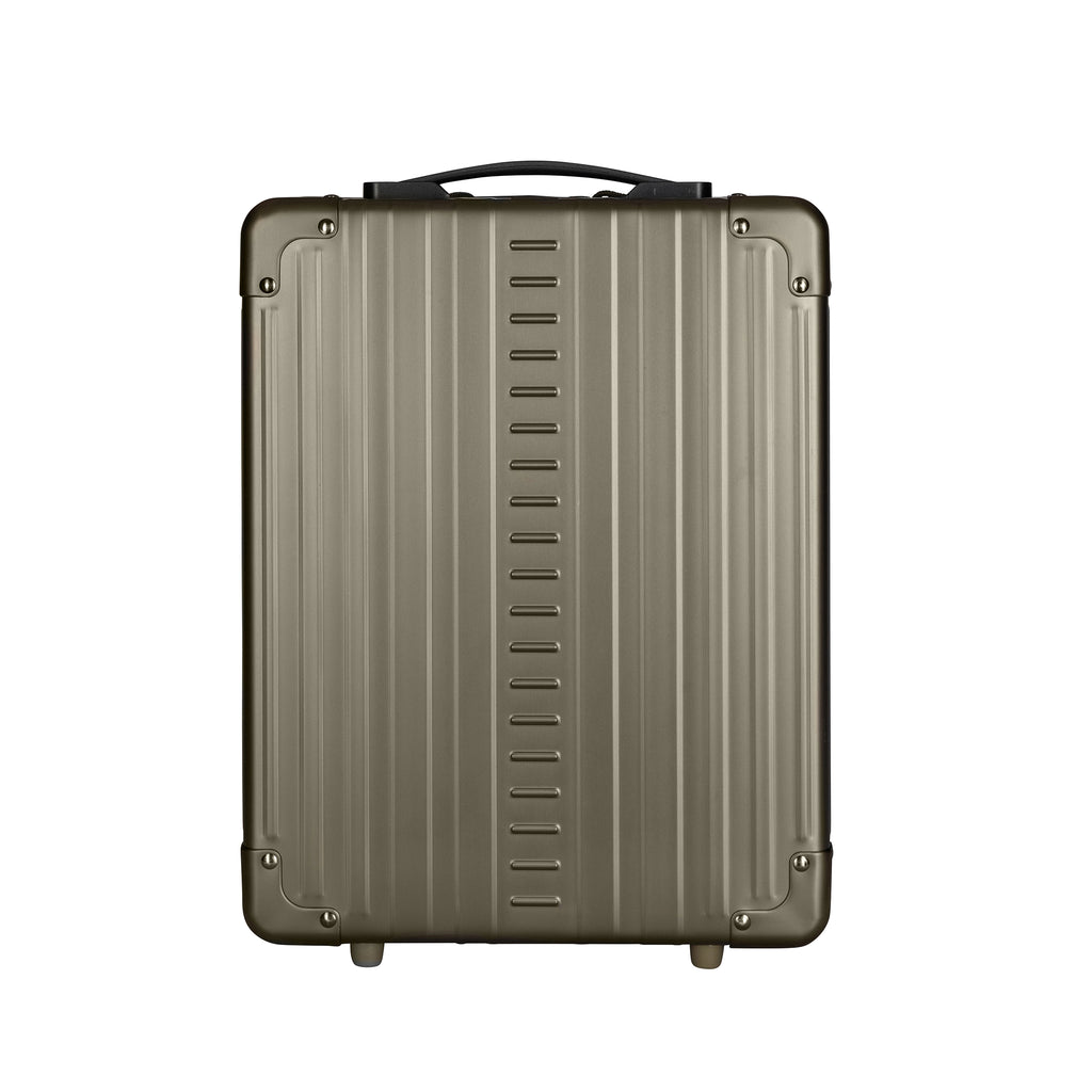 Showcases a sleek, ridged, metallic grey carry-on suitcase with a black handle, designed for durable travel.

