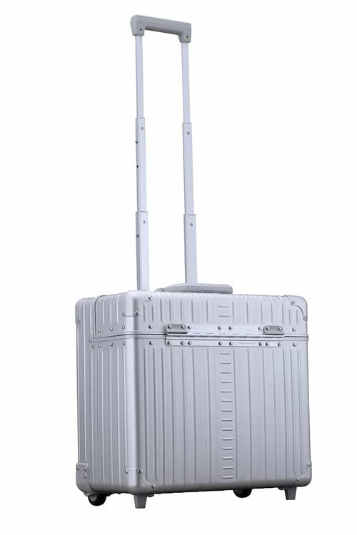 A silver aluminum rolling suitcase stands upright with its handle extended.
