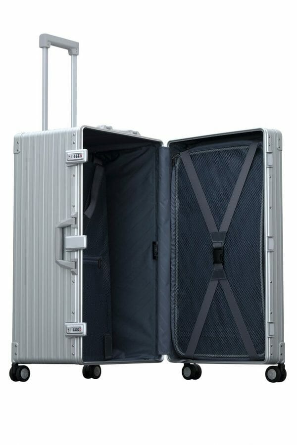 Silver Platinum 30-inch Aluminum Trunk – International Checked Spinner Case|A close-up of the silver suitcase’s high-density double quad wheels, designed for smooth 360-degree rotation. The aluminum side handle is visible, offering an alternative carrying option for convenience.|The platinum suitcase is fully opened, revealing a spacious interior with a fitted packing cube and a compression panel 