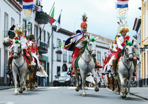 group of men with colorful hats in a parade of azores on horses 