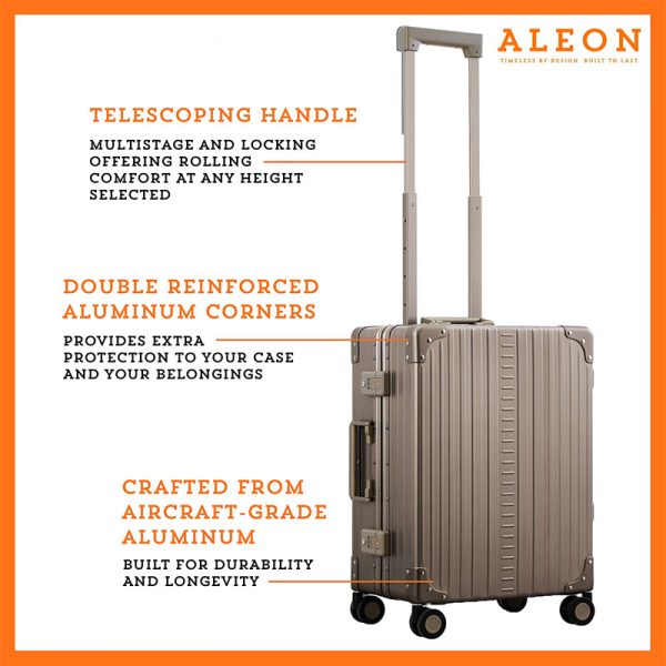 A polished aluminum ALEON 21" Carry-On stands upright on a glossy airport floor, reflecting ambient lighting. Its durable, hard-shell construction and smooth wheels embody modern travel efficiency.