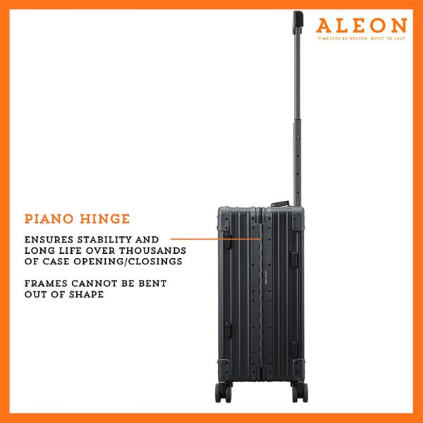 A polished onyx aluminum ALEON 21" Carry-On stands upright on a glossy airport floor, reflecting ambient lighting. Its durable, hard-shell construction and smooth wheels embody modern travel efficiency.