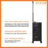 The ALEON 21" black Carry-On rests beside a plush airport lounge chair, its refined metallic finish complementing the sophisticated travel setting. Designed for durability and elegance, it exudes premium craftsmanship and functionality.
