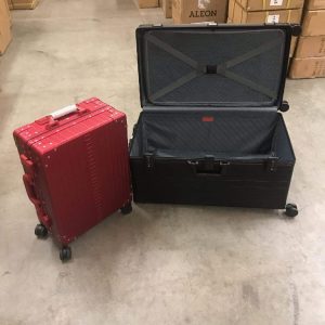 Rolling-trunk-luggage on its side with a carry on luggage next to it in red